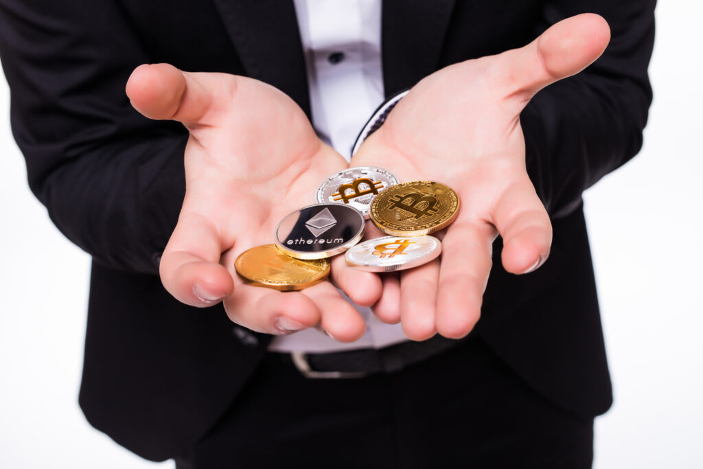 man holds different crypto coins his hands white