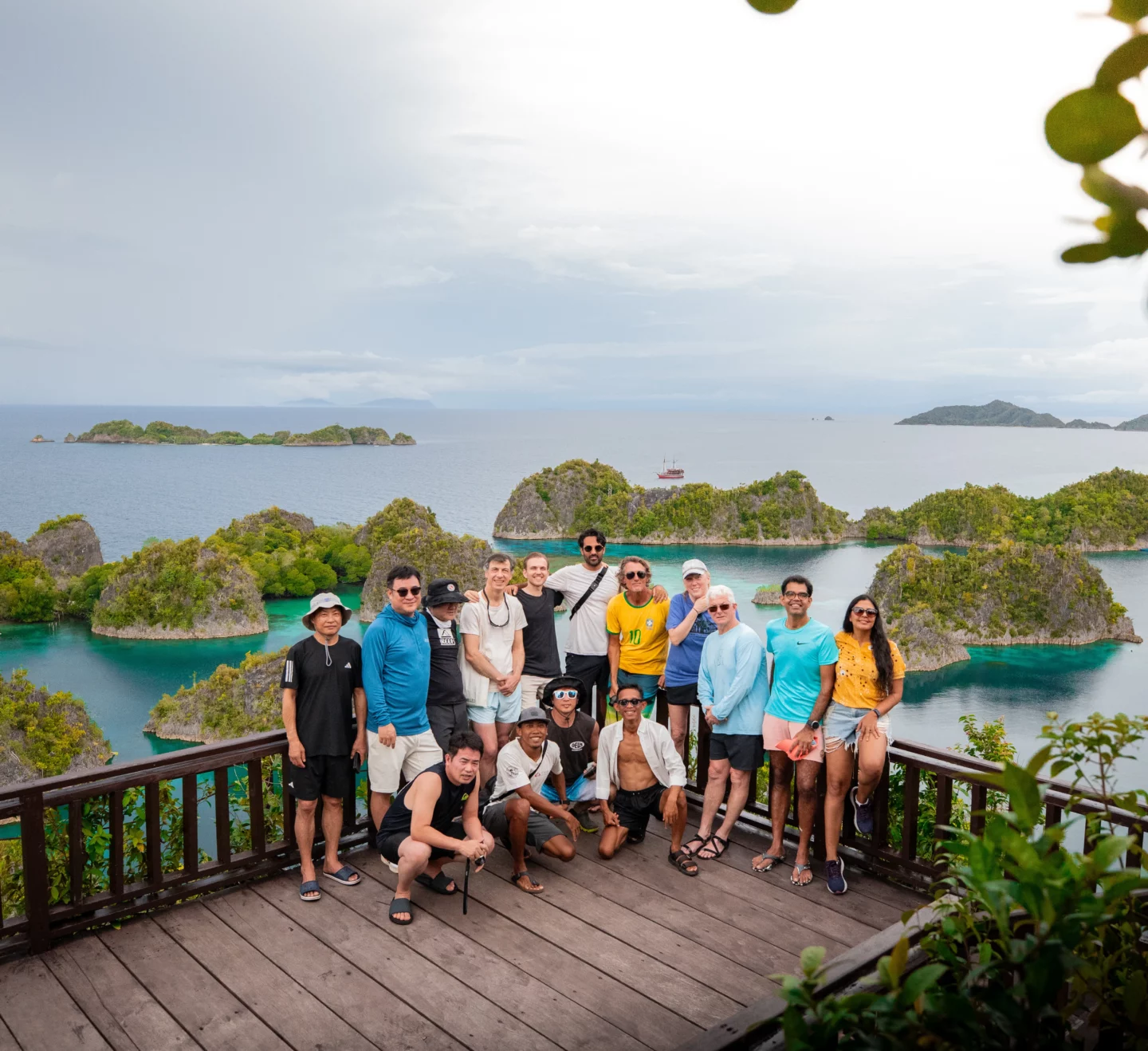 Group photo of divers at a viewpoint overlooking the stunning islands of Raja Ampat, highlighting the camaraderie of a Raja Ampat Liveaboard trip.