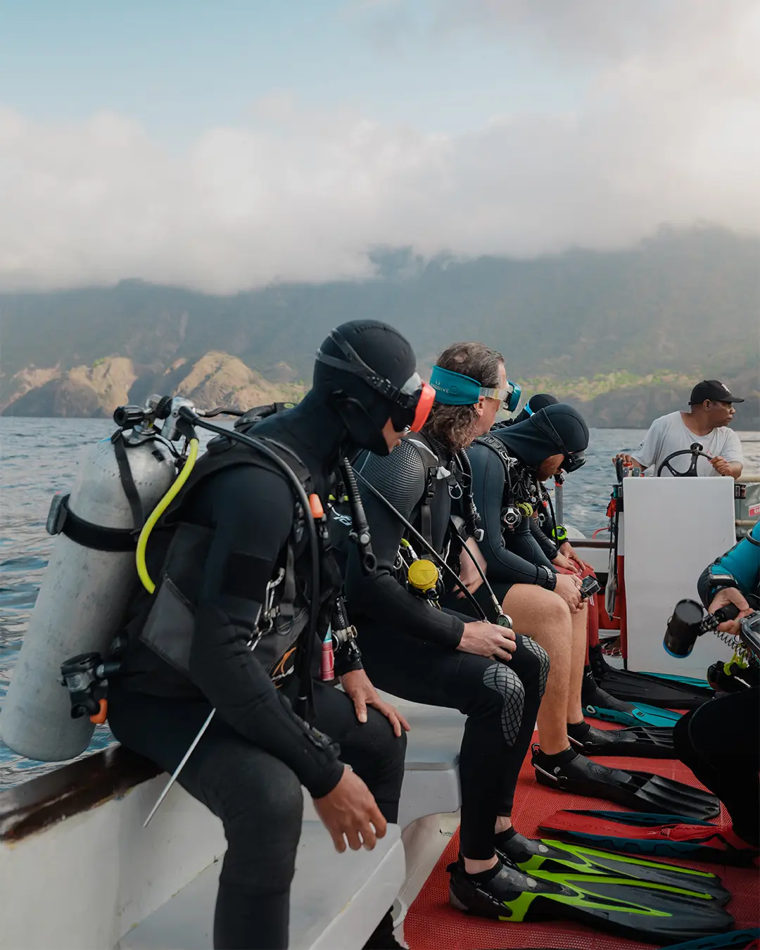 Scuba divers preparing for a backroll entry into the crystal-clear waters