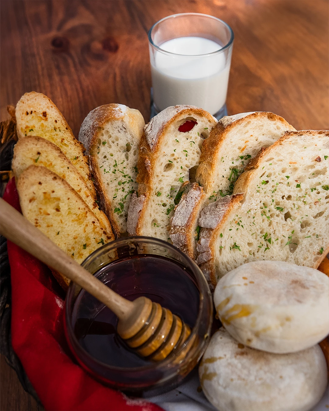 Artisan bread basket served with honey and a jug of milk.