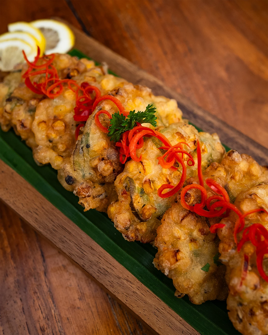 Golden corn and vegetable fritters topped with sliced red chili.