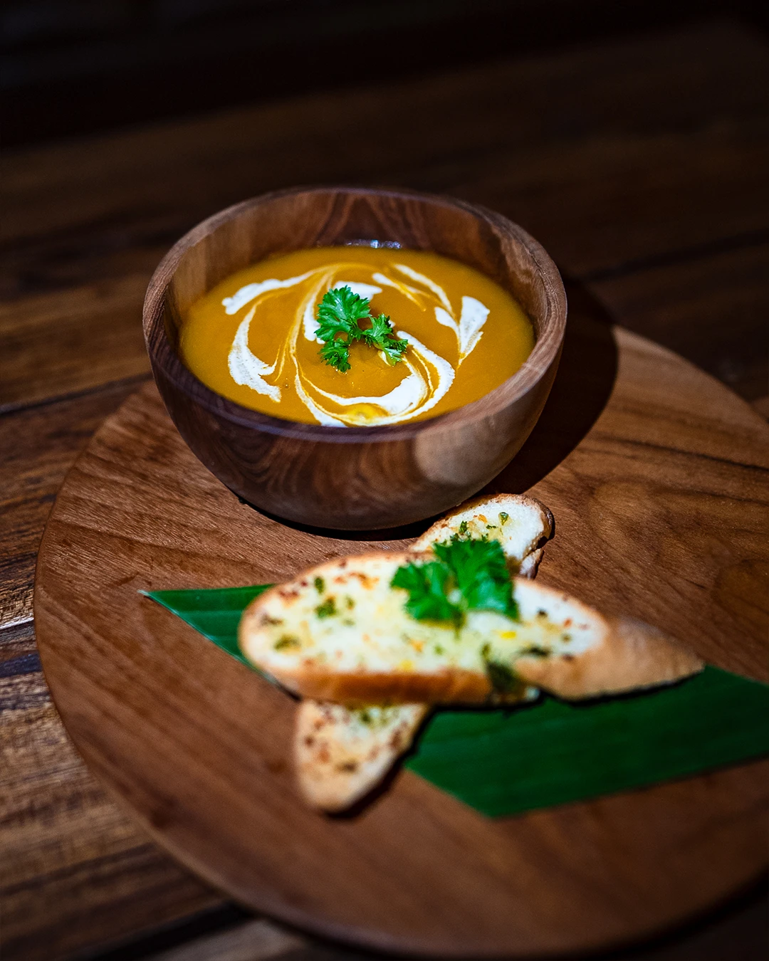 Warm bowl of creamy pumpkin soup served with crunchy garlic bread.