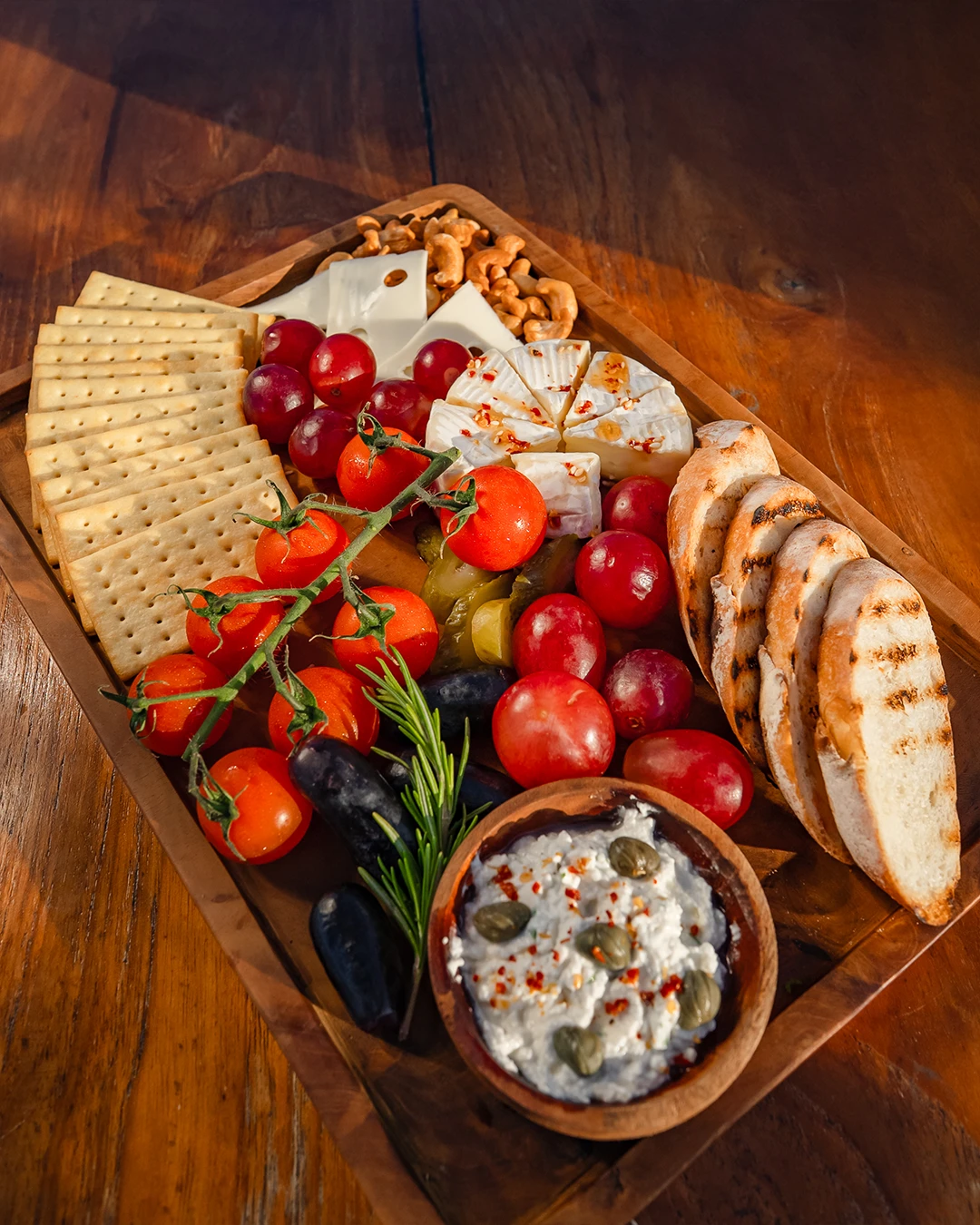Grazing board with cheese cubes, cherry tomatoes, and appetizers.