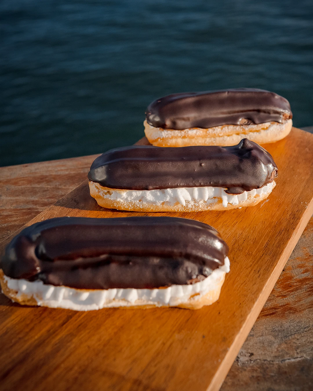 Cream-filled chocolate eclairs served on a dessert platter.