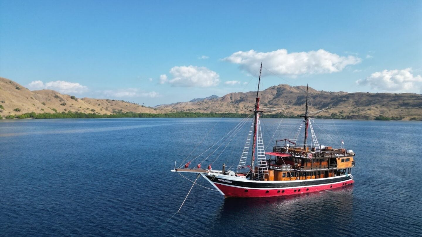 La Galigo liveaboard vessel sailing through calm Komodo waters, offering a comfortable dive base for exploring remote reefs and islands
