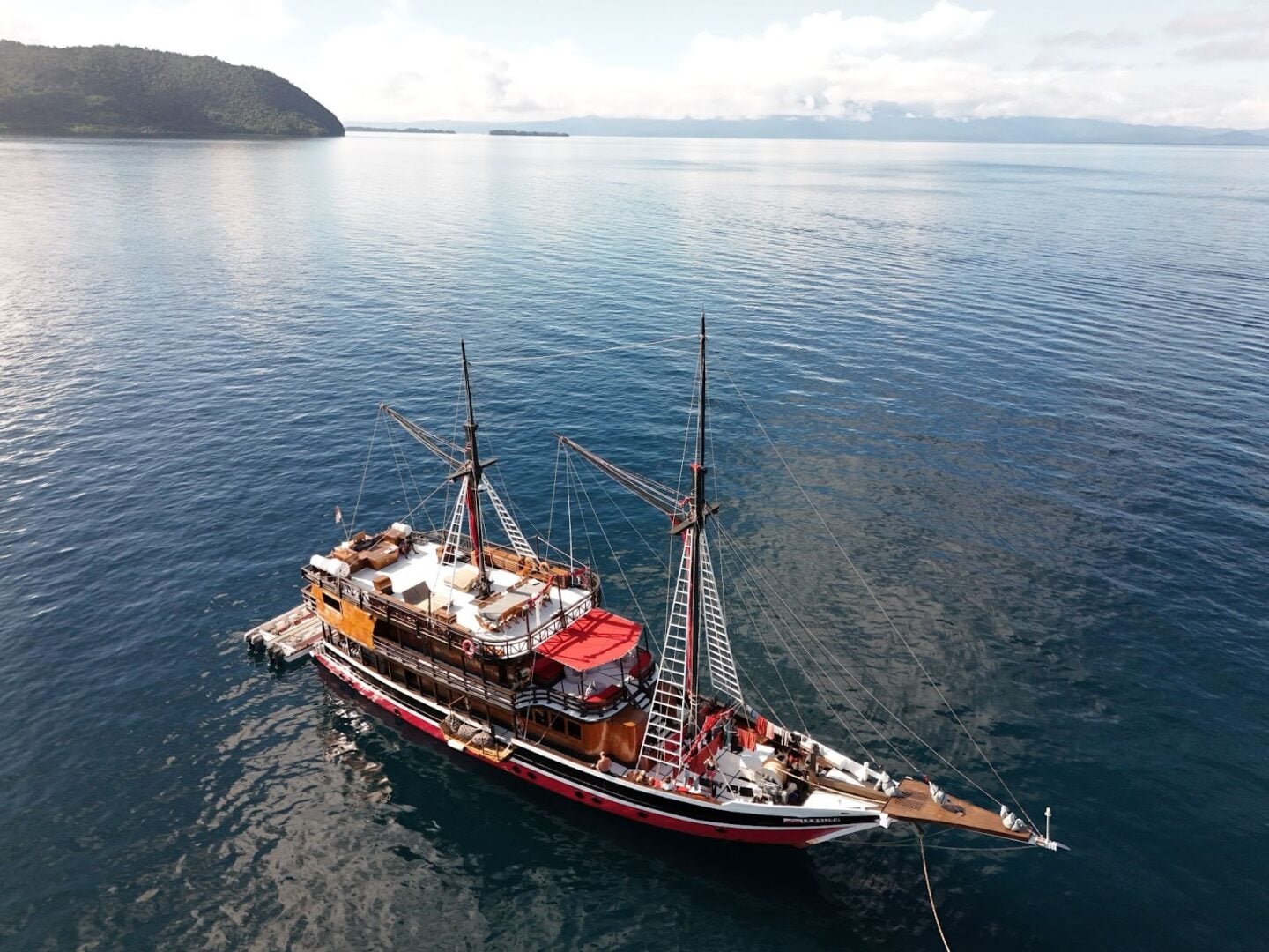 La Galigo liveaboard vessel anchored in clear tropical waters, showcasing a spacious wooden dive boat designed for comfortable diving expeditions